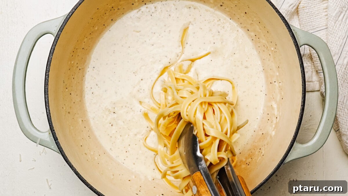 Creamy Chicken Alfredo Perfection 6 Tossing cooked fettuccine in creamy Alfredo Sauce in a large pot, ensuring every noodle is coated.