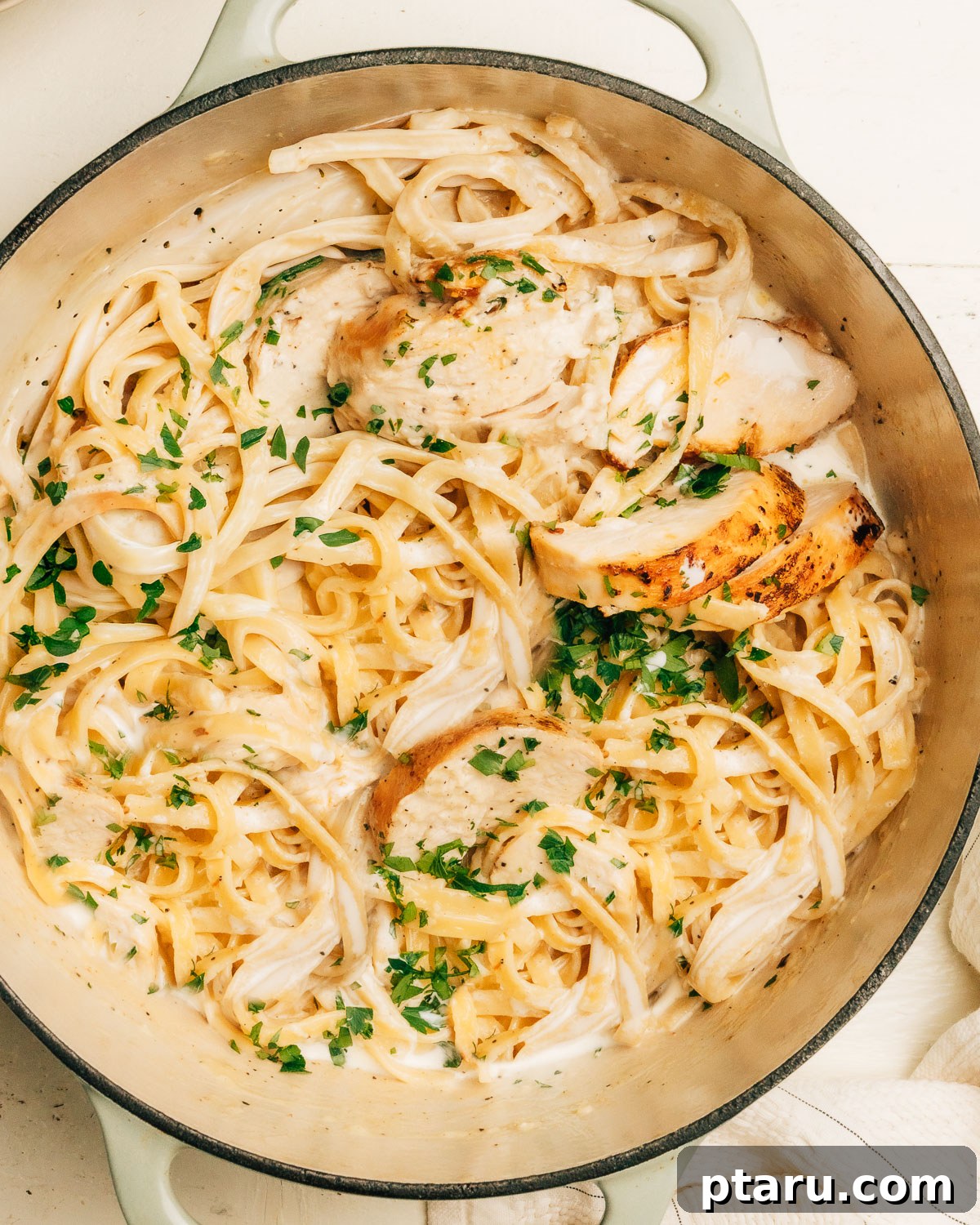 Creamy Chicken Alfredo Perfection 8 Close up of creamy chicken Alfredo showing fettuccine coated in parmesan sauce and garnished with fresh green herbs.