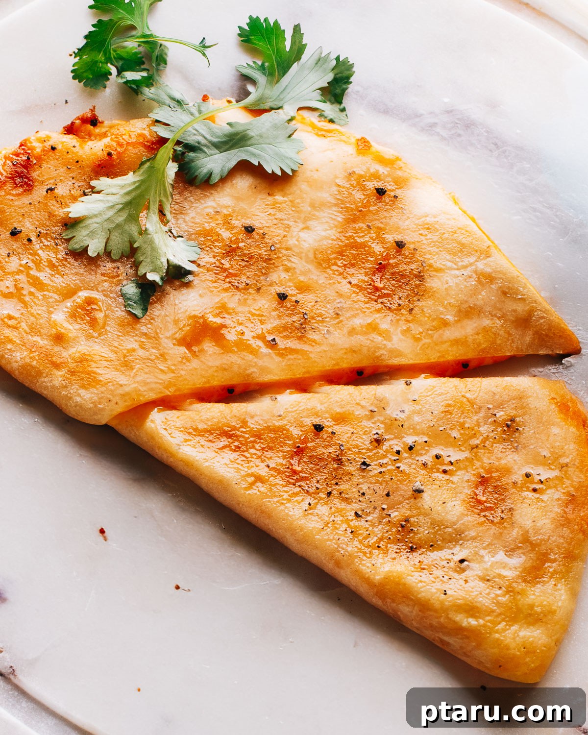 Fiesta Chicken Quesadilla 2 Crispy and golden chicken quesadilla recipe on a marble plate, garnished with fresh cilantro.