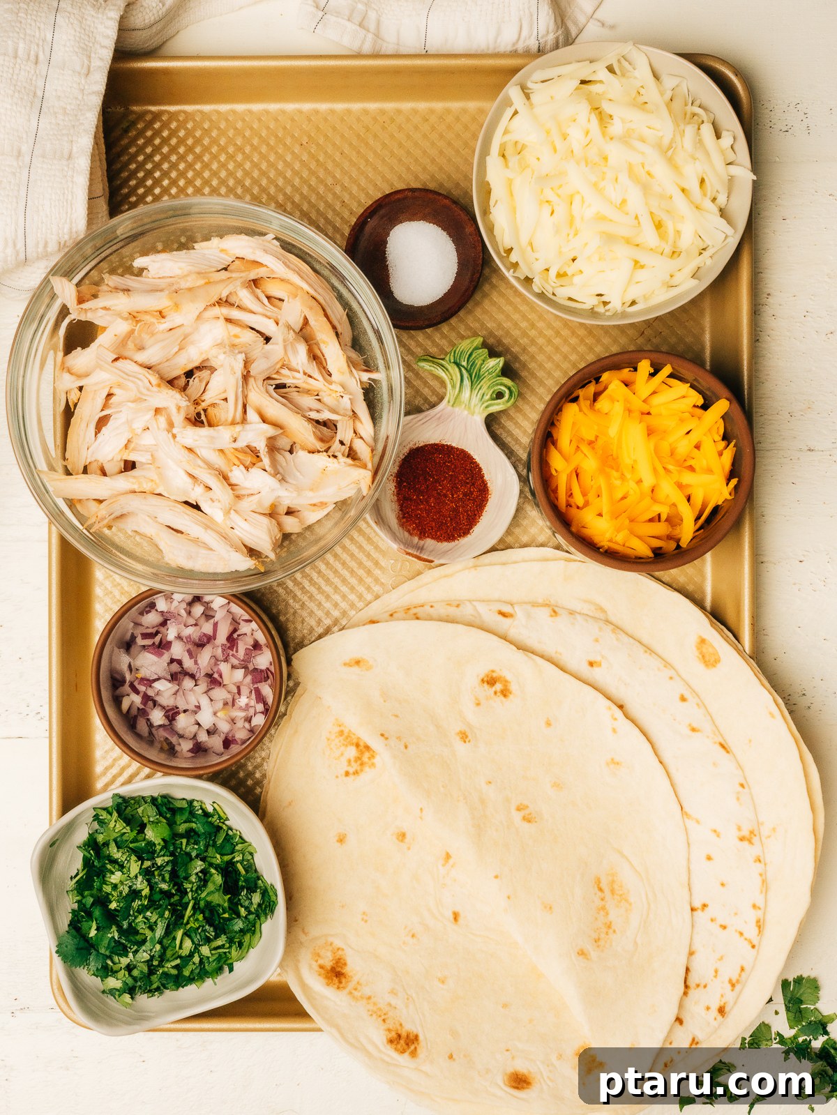 Fiesta Chicken Quesadilla 3 Chicken quesadilla ingredients laid out on the counter in a mise en place style, showcasing cheese, chicken, tortillas, and spices.