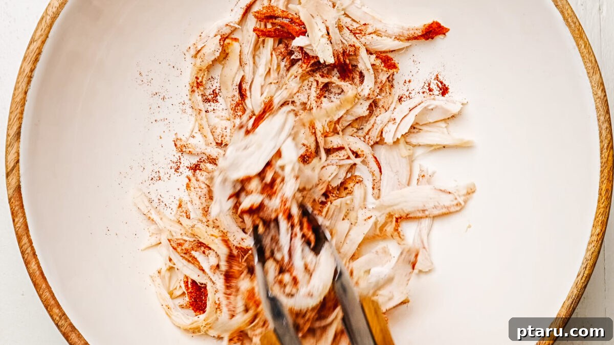 Fiesta Chicken Quesadilla 5 Shredded cooked chicken being tossed with chili powder and salt in a mixing bowl.