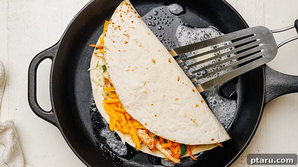 Fiesta Chicken Quesadilla 7 A chicken quesadilla being cooked in a large skillet with melted butter until golden brown on the first side.