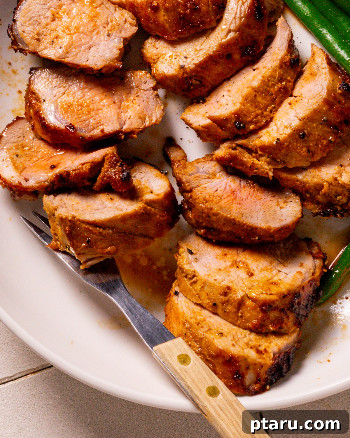 Melt-in-Your-Mouth Pork Tenderloin Marinade 2 Perfectly sliced pork tenderloin medallions, glistening with a savory glaze, served on a plate ready to be enjoyed.