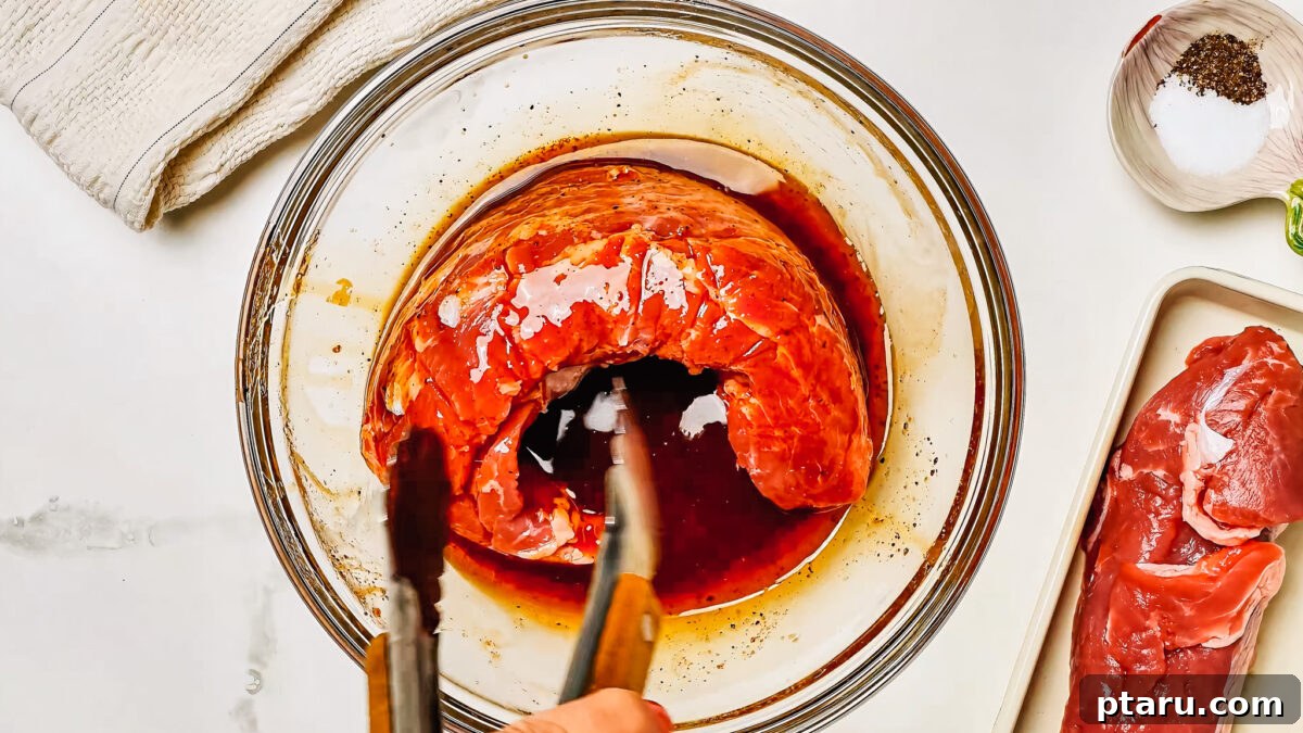 Melt-in-Your-Mouth Pork Tenderloin Marinade 5 A pork tenderloin submerged in the rich marinade within a shallow dish, highlighting the marinating process.