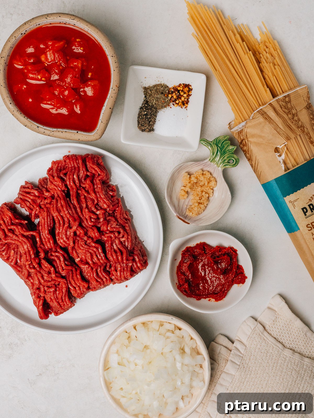 Hearty Beef Spaghetti Made Simple 3 Ingredients for ground beef spaghetti laid out on a wooden surface.