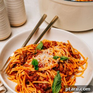Spaghetti with ground beef served in a bowl topped with Parmesan cheese