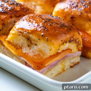 Buttery Honey-Glazed Ham & Cheese Sliders Recipe 9 Close-up of a single ham and cheese slider with melted cheese pulling down the side.