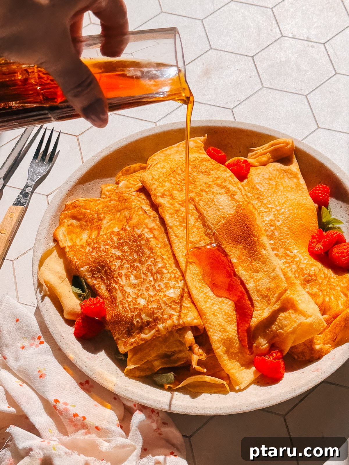 Classic French Crêpe Recipe: Thin Pancakes for Sweet & Savory Filling 2 Finished French crepe recipe on a plate with maple syrup and raspberries.