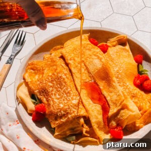 Classic French Crêpe Recipe: Thin Pancakes for Sweet & Savory Filling 4 Finished French crepe recipe on a plate with maple syrup and raspberries.