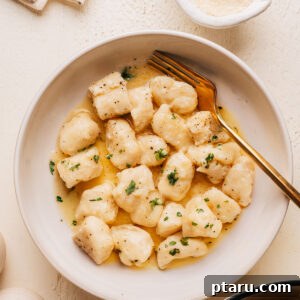 Bowl of homemade potato gnocchi in butter sauce with parmesan and fresh parsley.