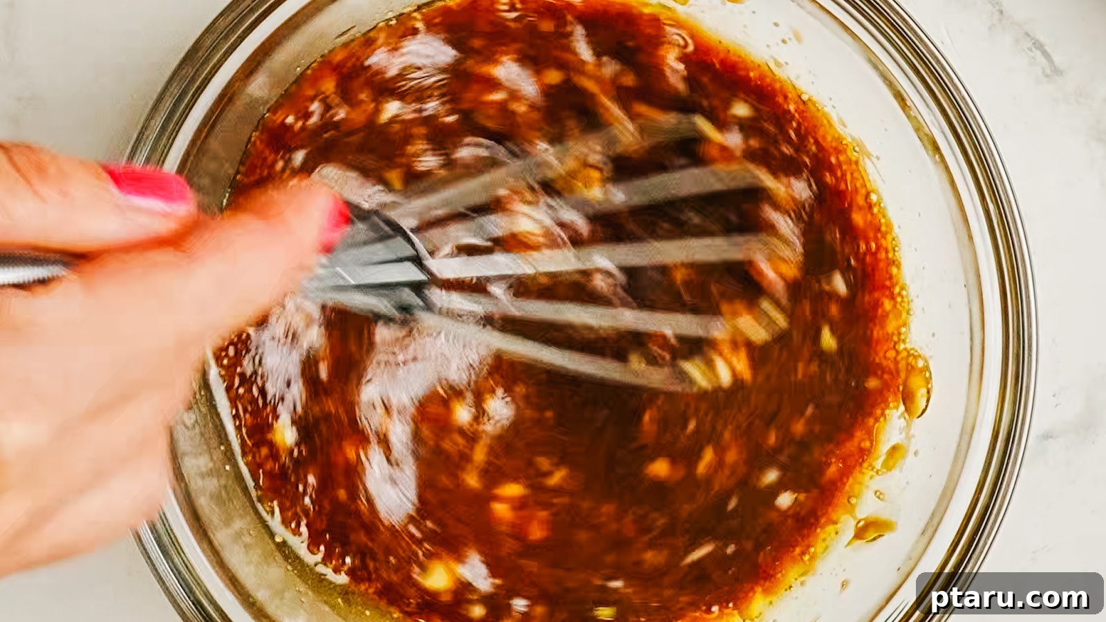 Whisking the dark balsamic marinade in a bowl.