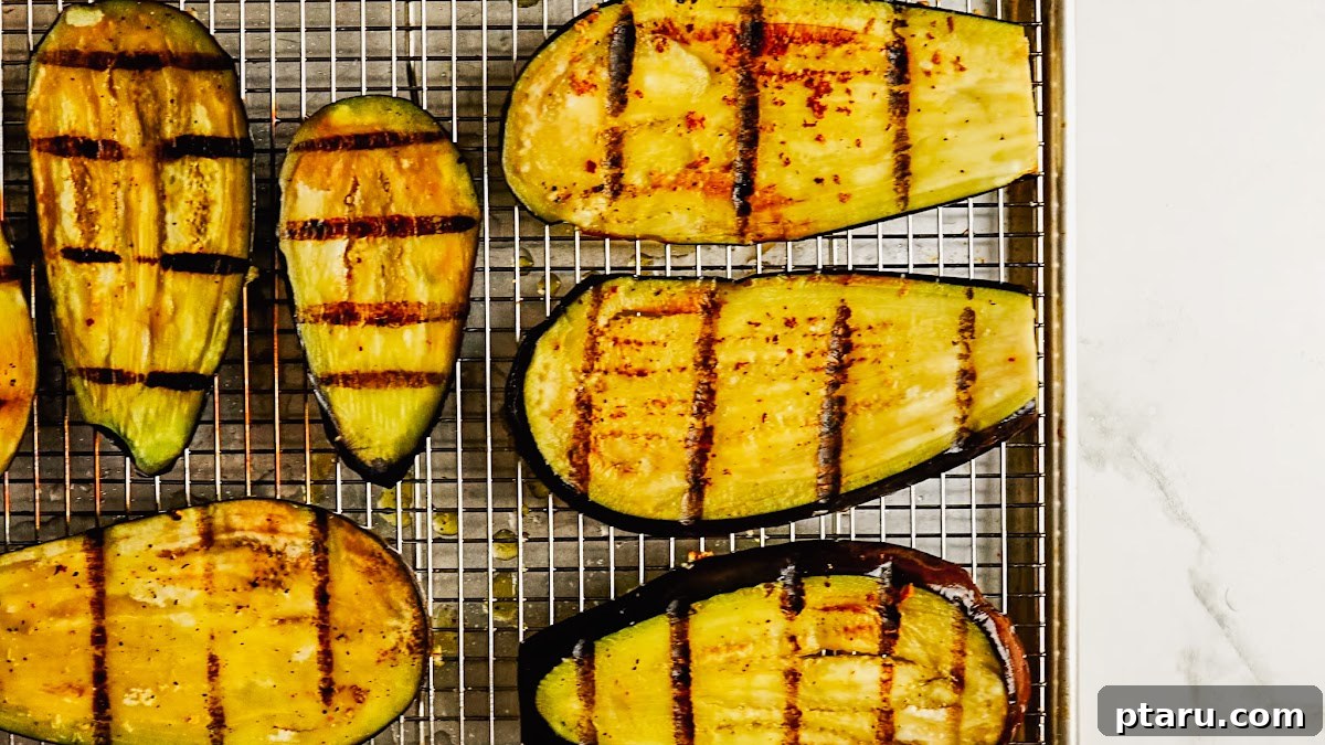 Grilled Eggplant with Garlic Oil and Whipped Feta 8 Grilled eggplant slices with char marks on the grill.