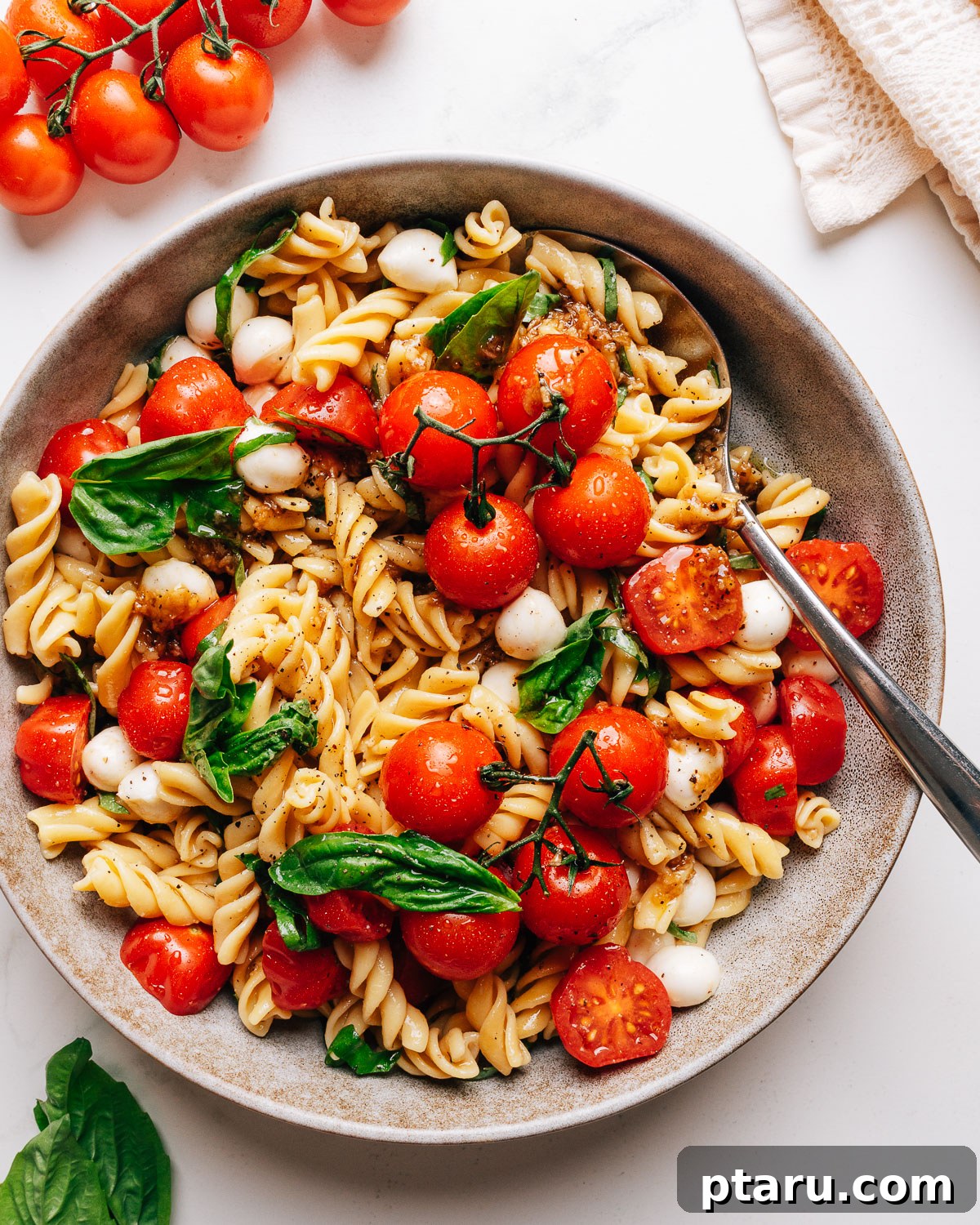 Caprese Pasta Salad with Cherry Tomatoes, Basil & Mozzarella 2 Caprese pasta salad in a bowl with cherry tomatoes, fresh mozzarella, and basil.