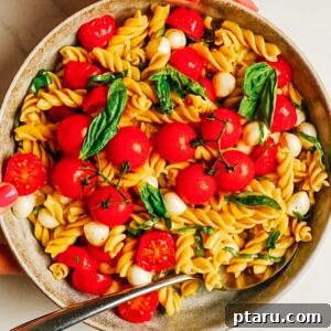 Caprese Pasta Salad with Cherry Tomatoes, Basil & Mozzarella 10 Caprese pasta salad in a bowl with cherry tomatoes, fresh mozzarella, and basil.