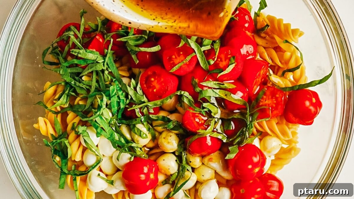 Caprese Pasta Salad with Cherry Tomatoes, Basil & Mozzarella 7 Balsamic dressing poured over caprese pasta salad before tossing.