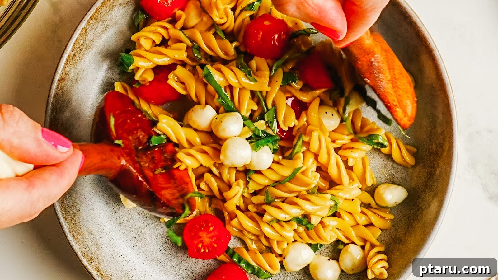 Caprese Pasta Salad with Cherry Tomatoes, Basil & Mozzarella 8 A served portion of caprese pasta salad with wooden servers.