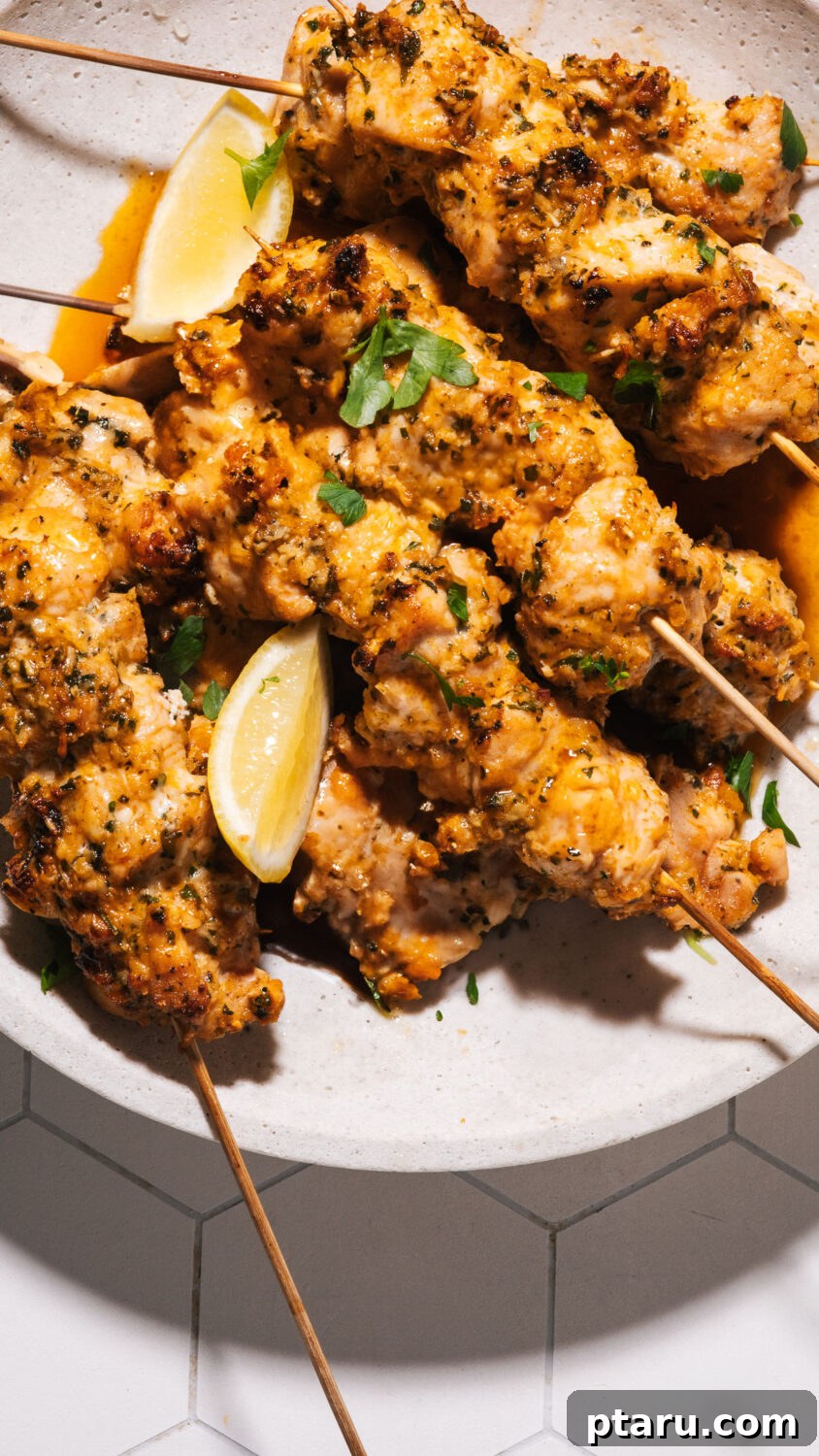 Chicken skewers on a plate with lemon wedges.