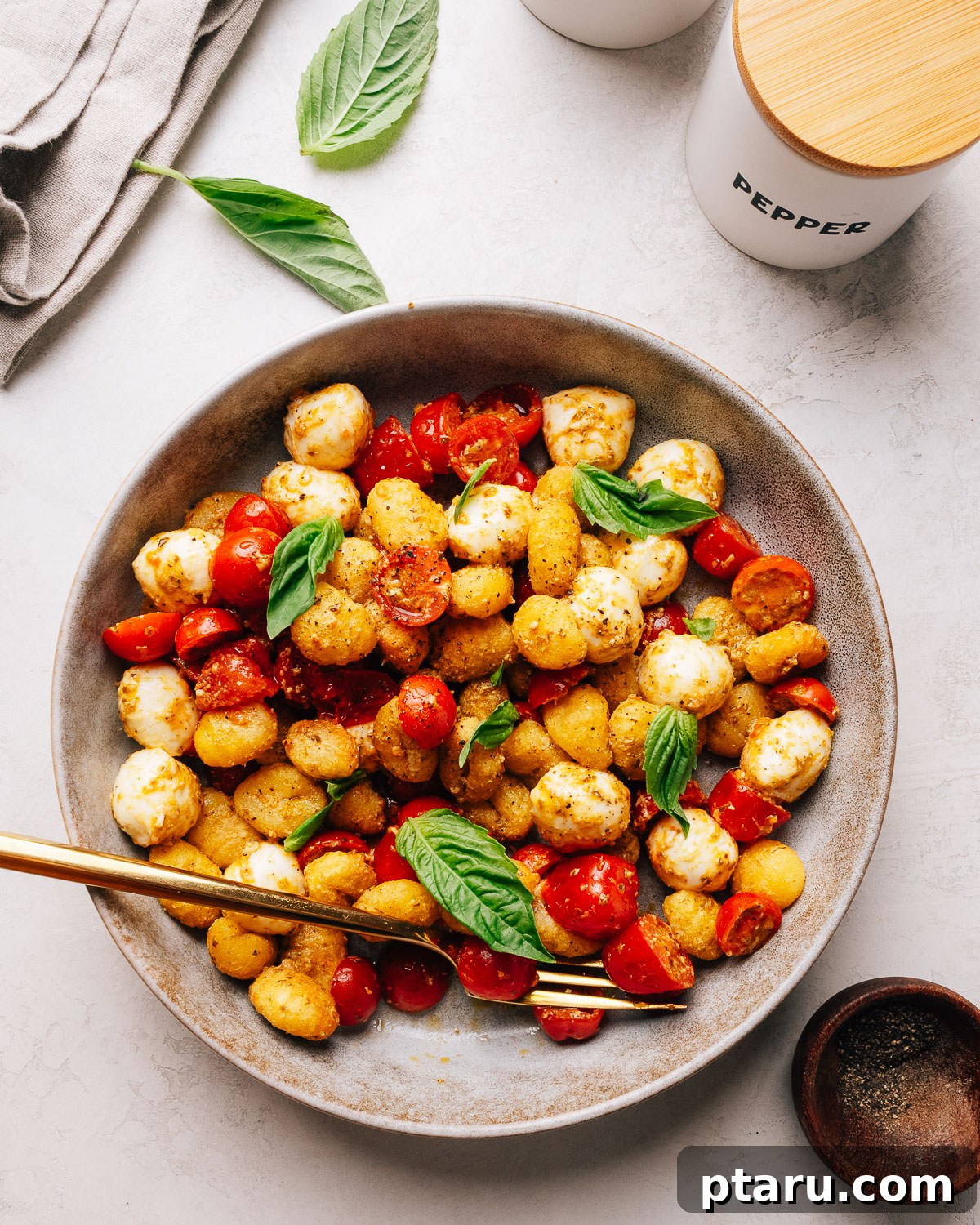 Crispy gnocchi salad with pesto, cherry tomatoes and bocconcini in a serving bowl.