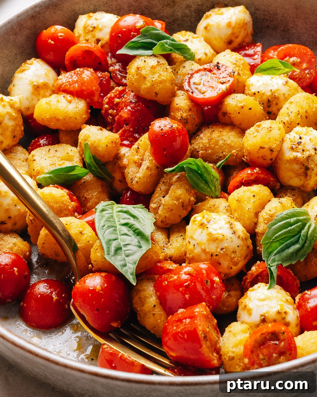 A plated portion of gnocchi salad with golden crisp gnocchi and fresh basil.
