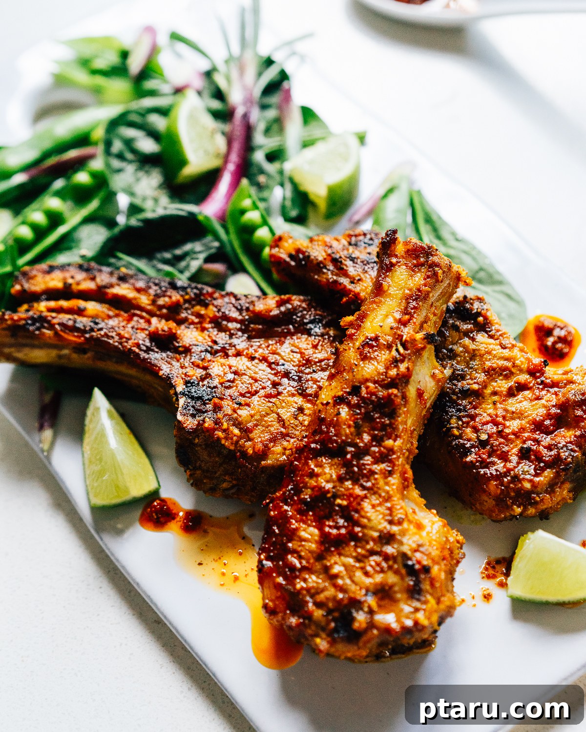 22 Summer Grilling Recipes Everyone Will Love 13 Grilled Indian lamb chops on a plate with lime wedges and salad.
