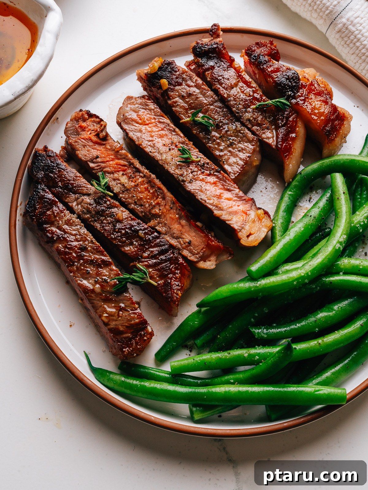 Pan-Seared Garlic Butter Steak in 15 Minutes 2 Overhead of sliced garlic butter steak with green beans on a plate.