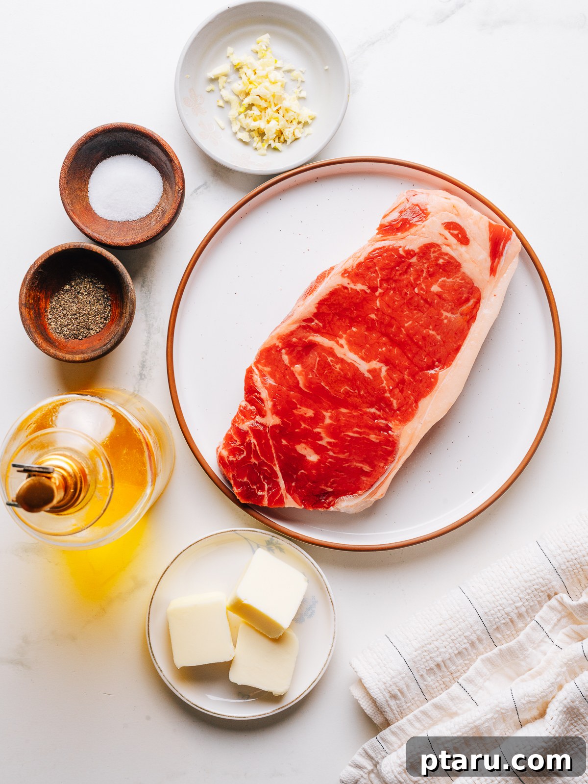 Pan-Seared Garlic Butter Steak in 15 Minutes 3 Raw steak with garlic, kosher salt, and black pepper laid out for garlic butter steak.