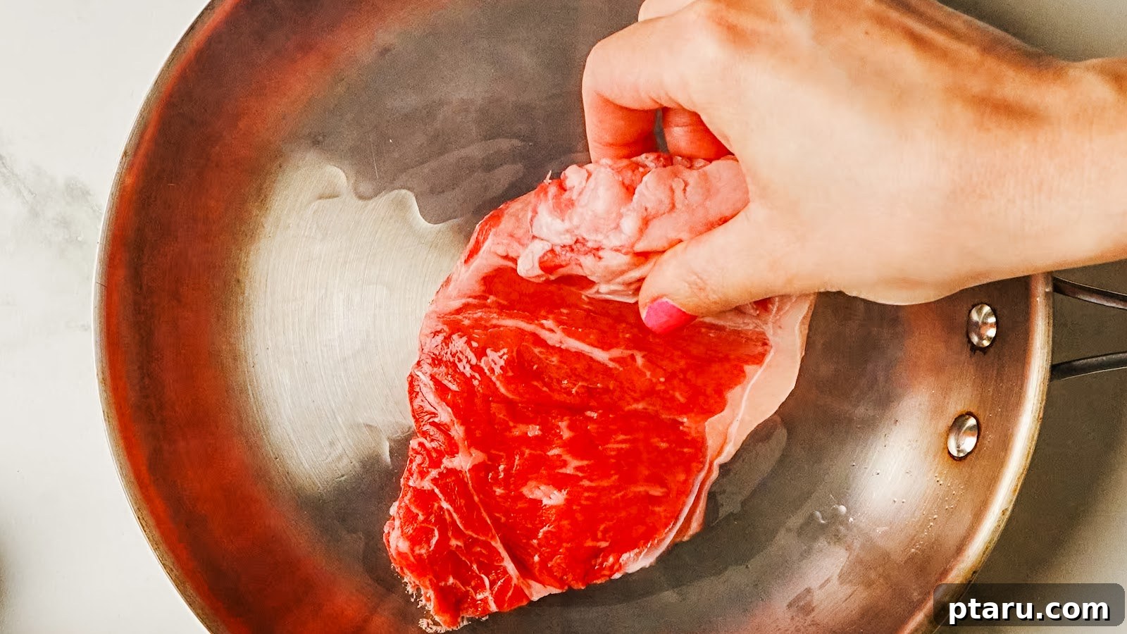Pan-Seared Garlic Butter Steak in 15 Minutes 4 Seasoned steak laid into a hot stainless pan to sear.