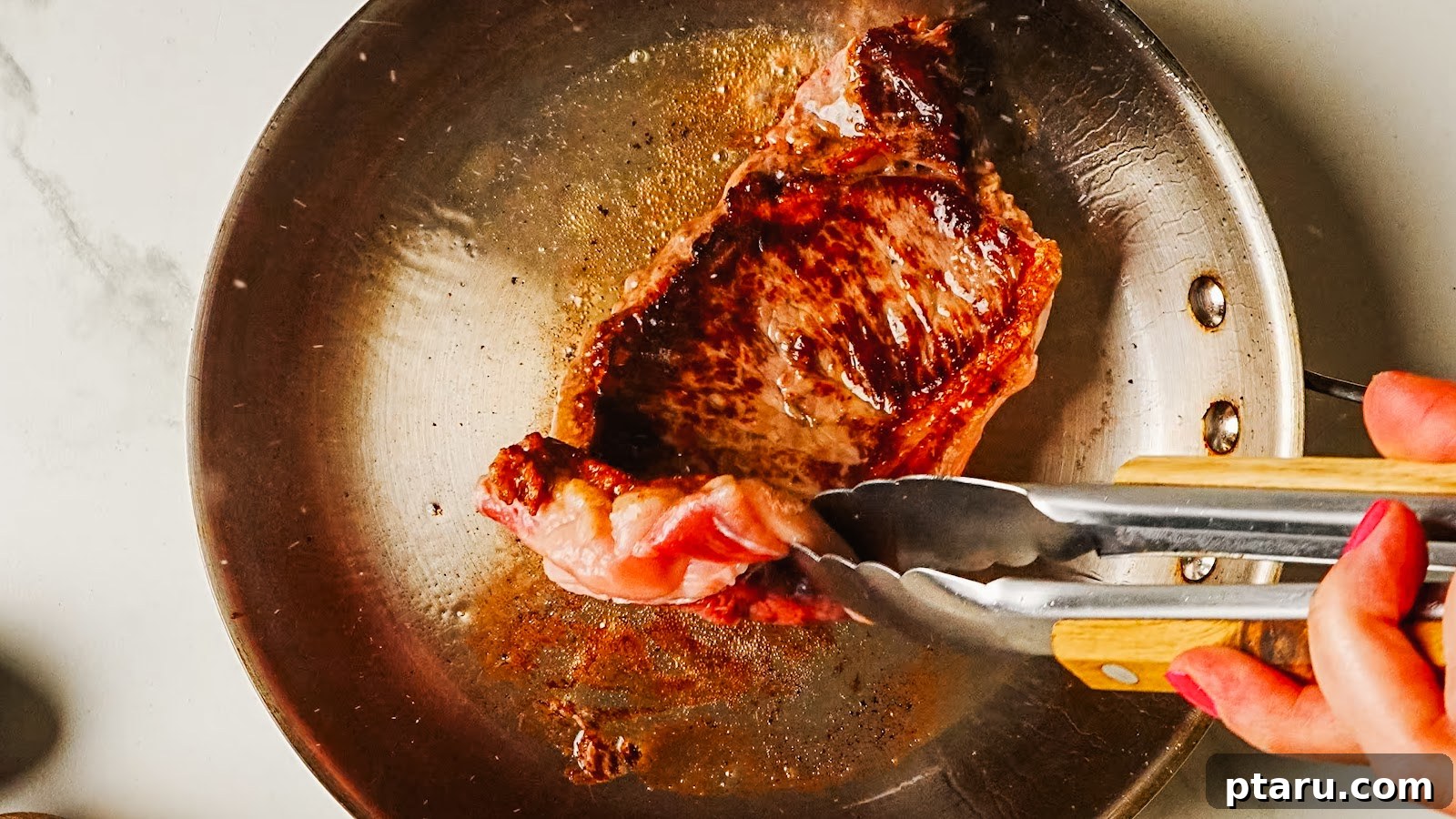 Pan-Seared Garlic Butter Steak in 15 Minutes 5 Steak searing with a deep brown crust, lifted with tongs.