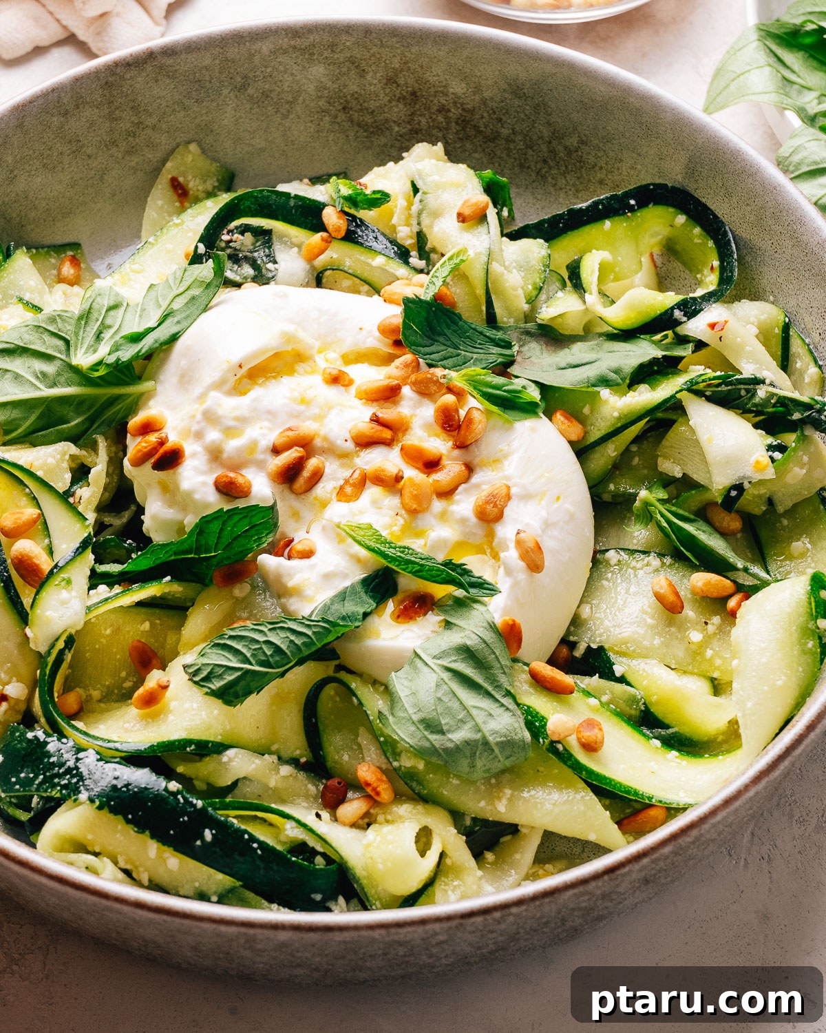 Zucchini Ribbon Salad with Lemon-Parmesan Vinaigrette 2 Zucchini salad with creamy burrata, toasted pine nuts, and fresh herbs in a bowl.