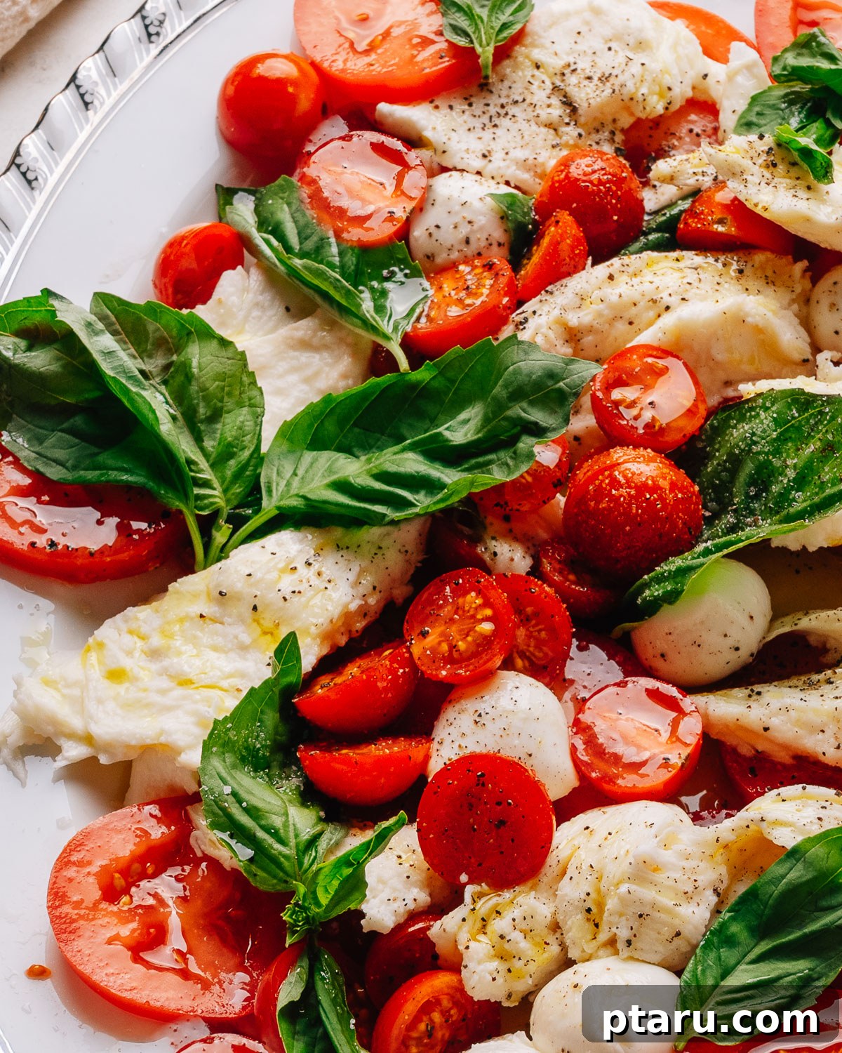 Authentic Caprese Salad with Cherry Tomatoes 2 Caprese salad recipe with cherry tomatoes on a platter with torn mozzarella, ripe tomatoes and fresh basil.