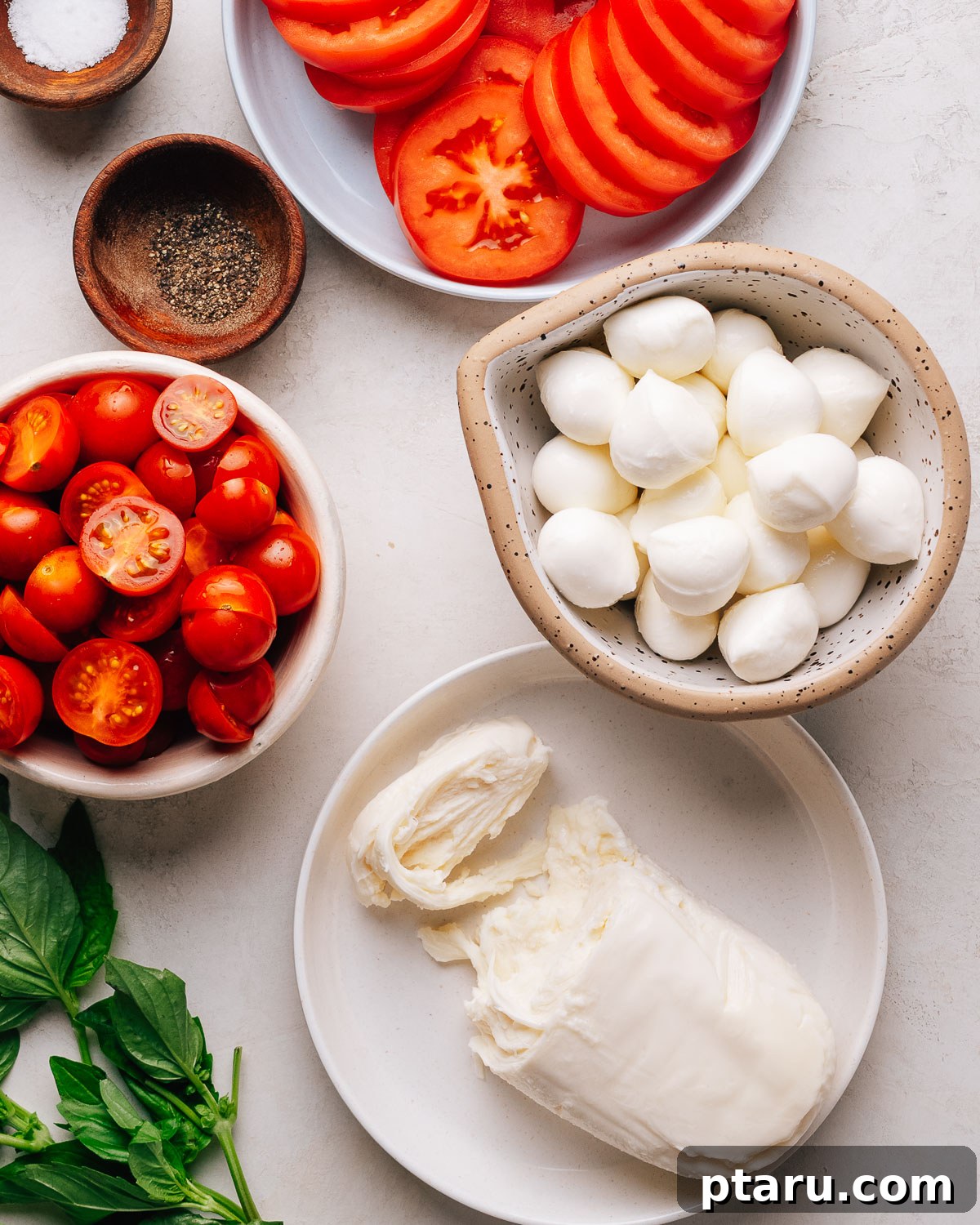 Authentic Caprese Salad with Cherry Tomatoes 3 Caprese Salad recipe ingredients with cherry tomatoes, mozzarella and basil on a white surface.