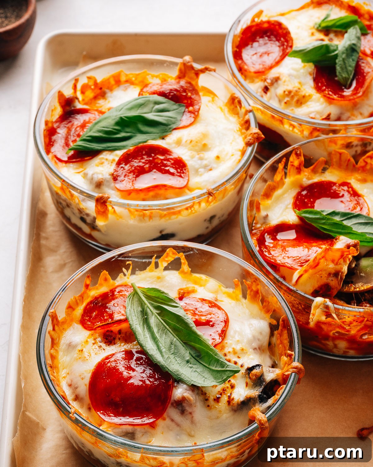 Loaded Cheesy Pizza Bowl Recipe 2 Pepperoni pizza bowls topped with fresh basil on a sheet pan.
