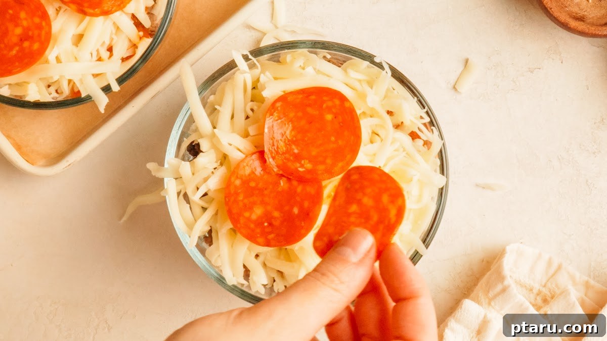 Loaded Cheesy Pizza Bowl Recipe 9 Step 3: pepperoni layered over shredded mozzarella in a glass pizza bowl.