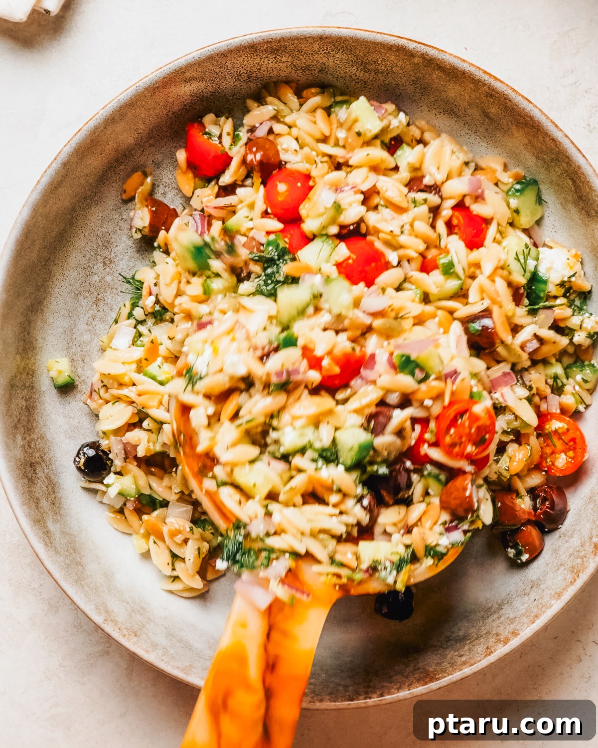 Orzo pasta salad with cucumber, cherry tomatoes, olives and feta in a bowl.