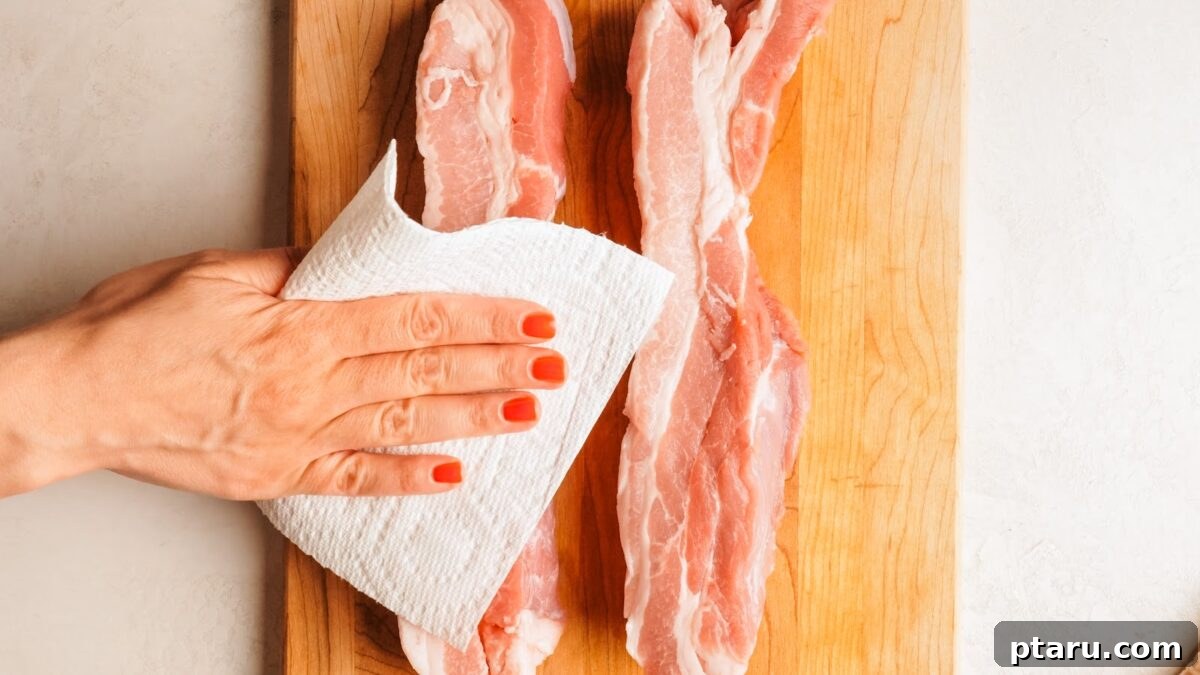 Slow-Roasted Pork Belly with Crispy Crackling 5 Raw skin-on pork belly slab being patted dry with a paper towel.