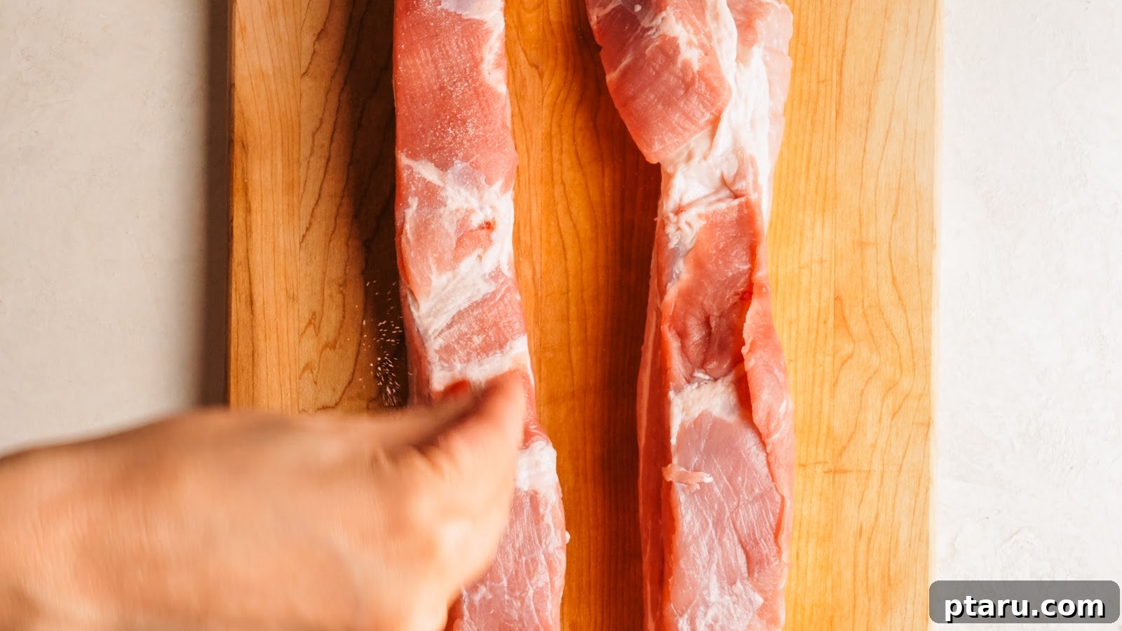 Slow-Roasted Pork Belly with Crispy Crackling 6 Seasoning the meat side of the pork belly on a cutting board.