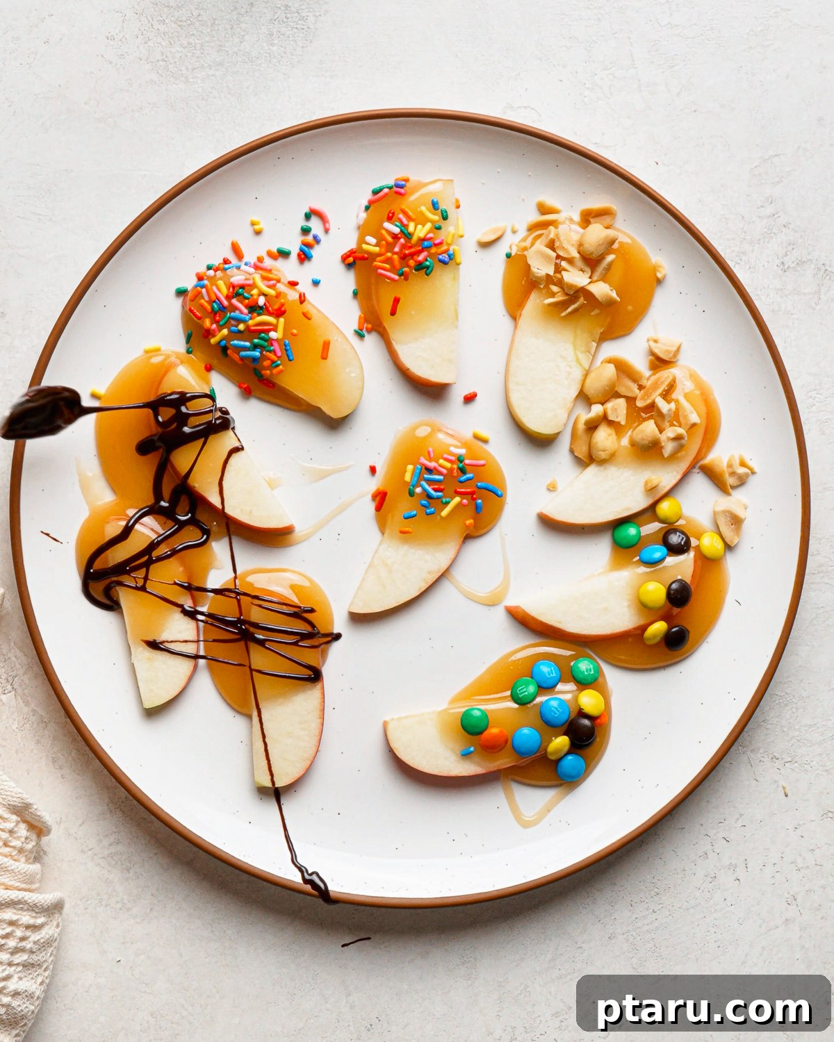Caramel Apple Slices with Homemade Caramel Sauce 2 Plate of caramel apple slices topped with chocolate drizzle, sprinkles, M&M’s and chopped peanuts.