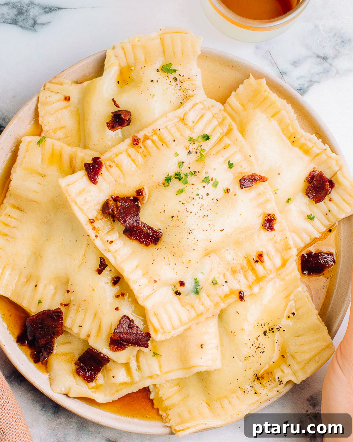 Pumpkin Ravioli Sauce: Brown Butter and Sage 2 Sauce for pumpkin ravioli served on a plate of cooked ravioli.
