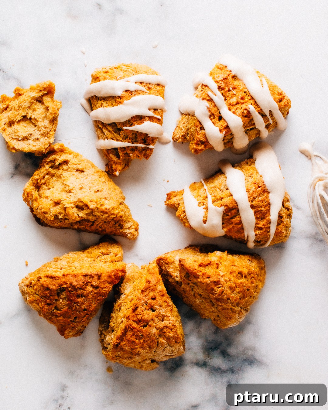 Soft Pumpkin Scones Recipe with Cinnamon Glaze 7 Overhead view of glazed and unglazed pumpkin scones on a marble counter.