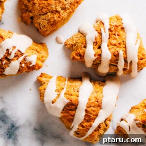 Soft Pumpkin Scones Recipe with Cinnamon Glaze 9 Pumpkin scones with cinnamon glaze on a marble surface.
