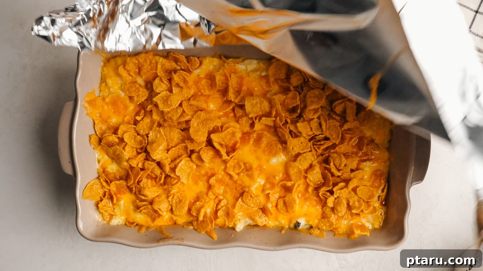 Funeral Potatoes: Cheesy Casserole with Cornflake Topping 11 Foil pulled back from the casserole to brown the cornflake topping.