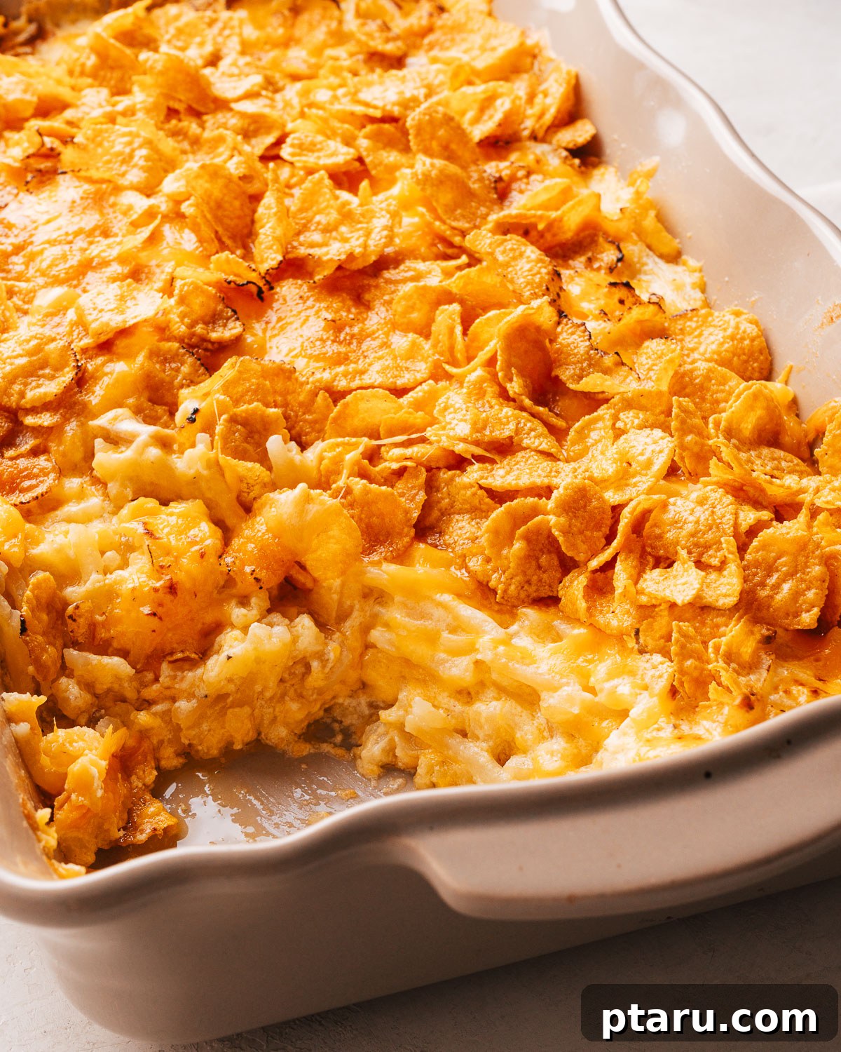 Funeral Potatoes: Cheesy Casserole with Cornflake Topping 4 Cheesy hash brown potato casserole in a baking dish.