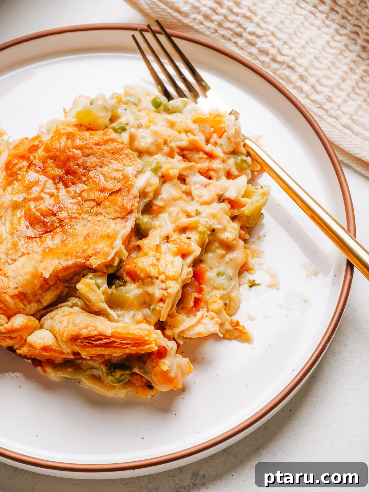 Creamy Chicken Pot Pie Casserole with Flaky Puff Pastry 4 A serving of chicken pot pie casserole on a plate with flaky puff pastry and creamy filling.