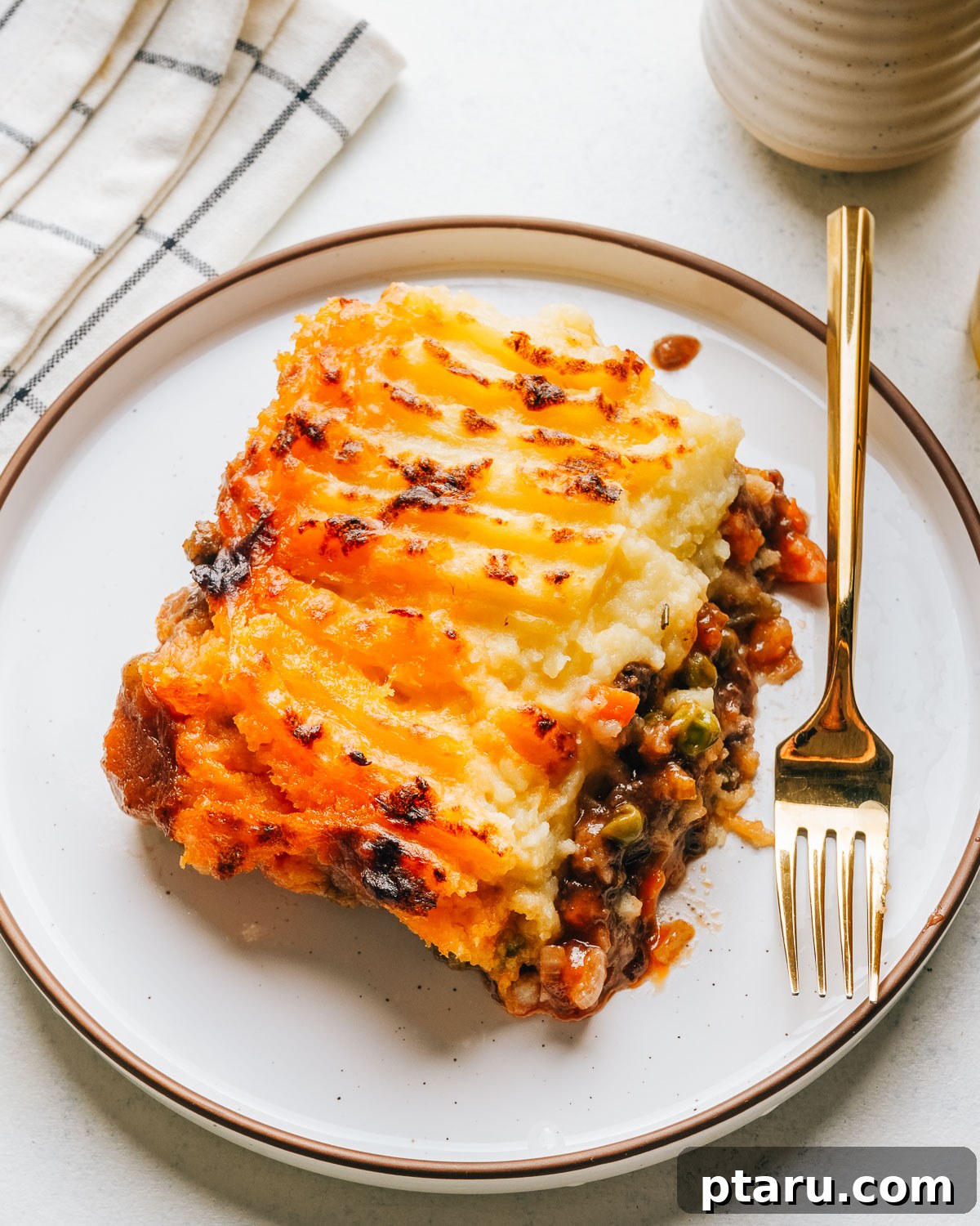 Classic Shepherd's Pie with Ground Beef or Lamb 13 A serving of shepherd's pie with browned mashed potato peaks and a gold fork.