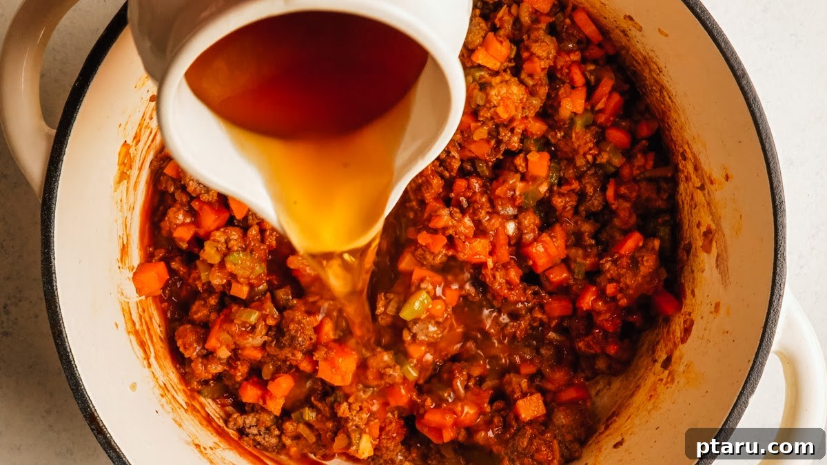 Classic Shepherd's Pie with Ground Beef or Lamb 9 Pouring beef broth into the pan to build the gravy.