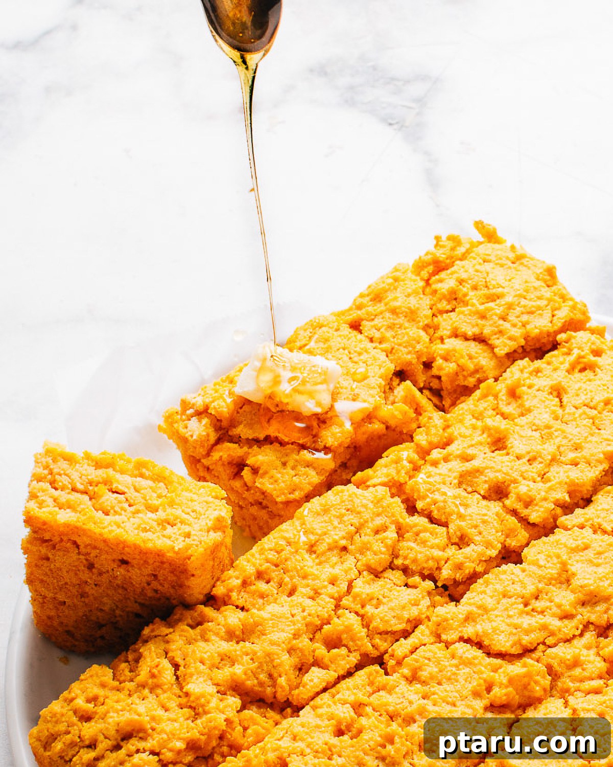 How to Make Moist Sweet Potato Cornbread 9 Honey drizzling onto a buttered square of sweet potato cornbread.
