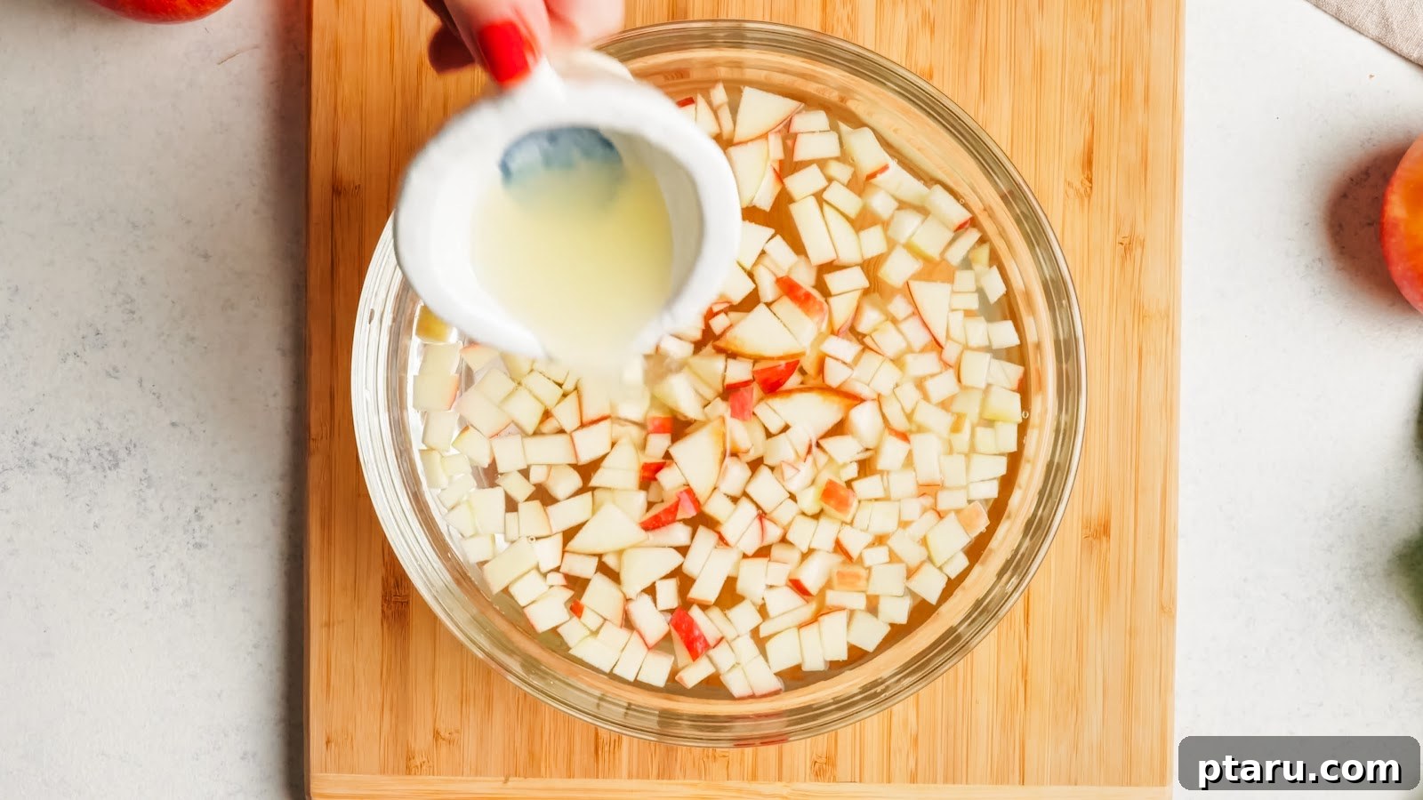 Classic Waldorf Salad with Apples, Grapes, and Walnuts 4 Lemon juice poured over diced apples in a glass bowl to keep the Waldorf salad from browning.