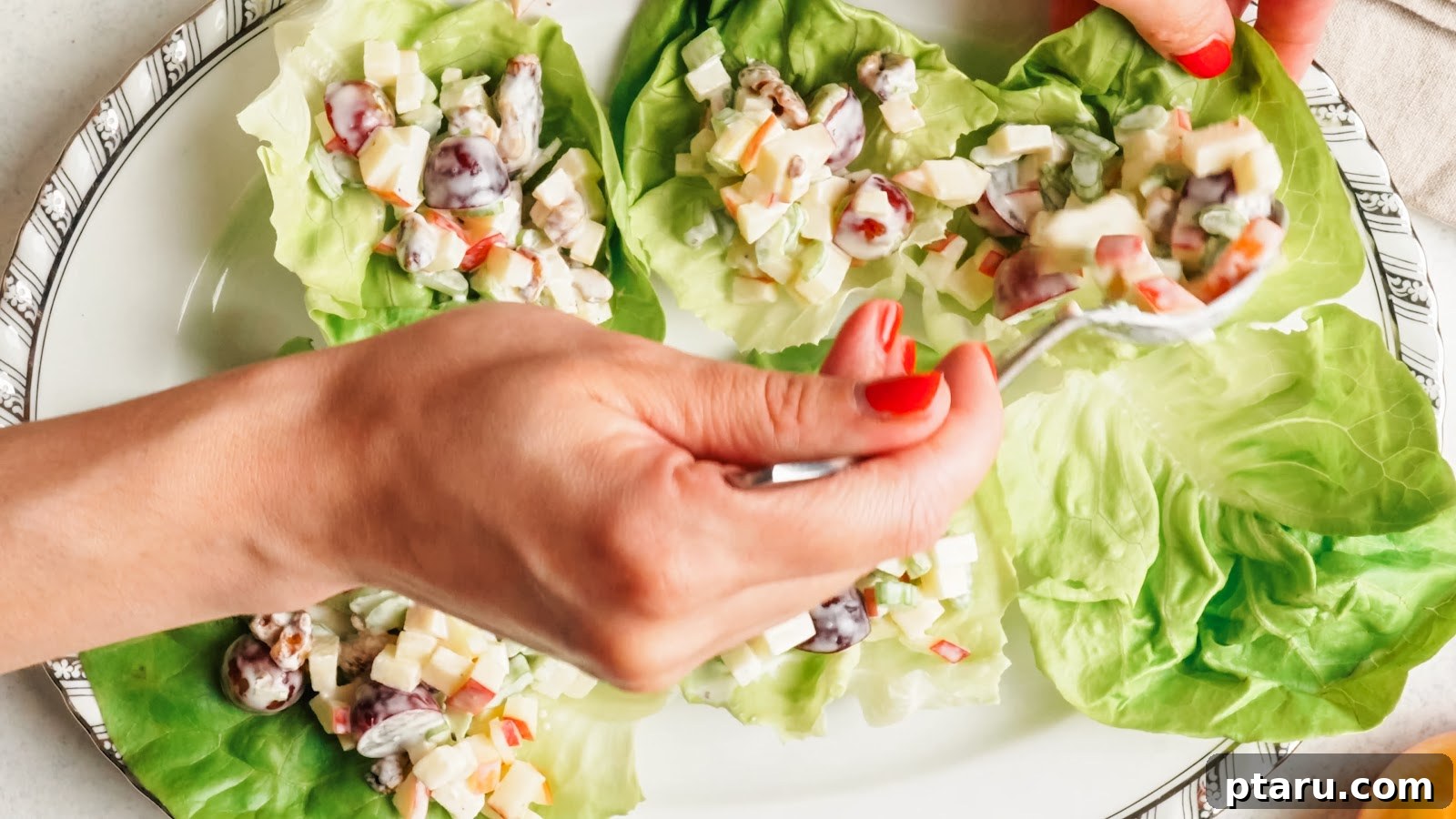 Classic Waldorf Salad with Apples, Grapes, and Walnuts 10 Spooning creamy apple salad into butter lettuce cups on a platter.