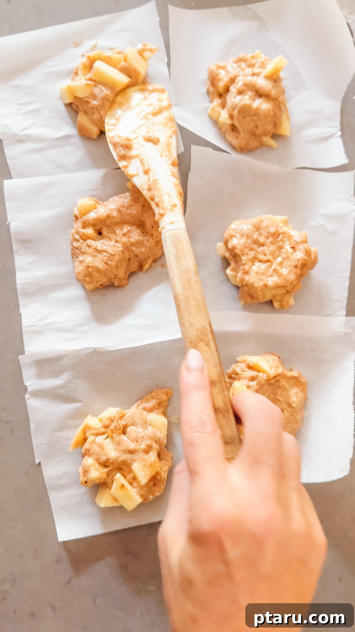 Crispy Homemade Apple Fritters with Cinnamon Glaze 5 Apple fritter dough portioned onto parchment squares and flattened with a spatula.