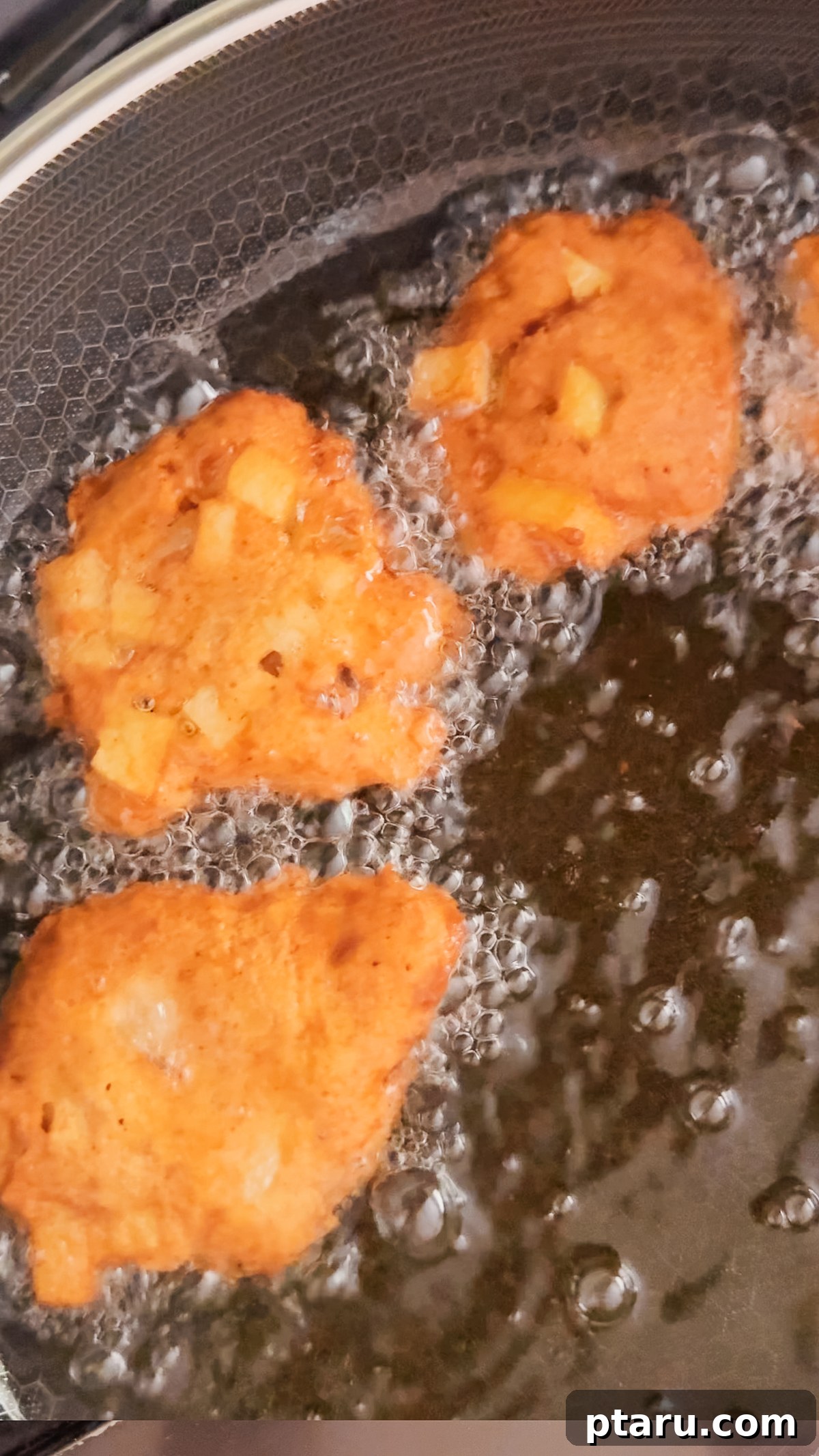 Crispy Homemade Apple Fritters with Cinnamon Glaze 8 Apple fritters frying until golden brown in hot oil.